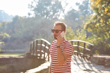 Parkta modern akıllı telefon kullanan genç bir adam..