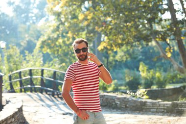 Parkta modern akıllı telefon kullanan genç bir adam..