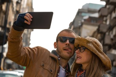 Şehirdeki sokakta selfie çeken genç bir çift..