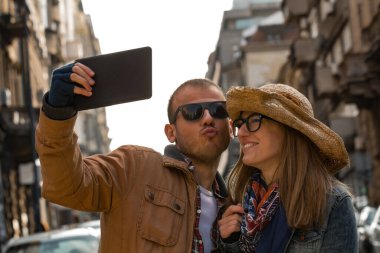 Şehirdeki sokakta selfie çeken genç bir çift..