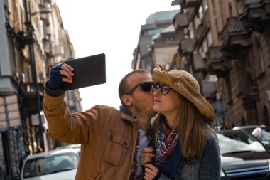 Şehirdeki sokakta selfie çeken genç bir çift..
