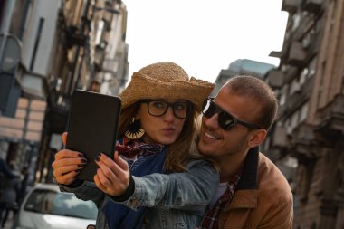 Şehirdeki sokakta selfie çeken genç bir çift..