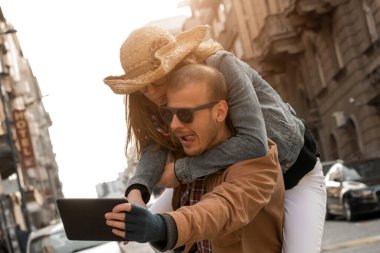 Şehirdeki sokakta selfie çeken genç bir çift..