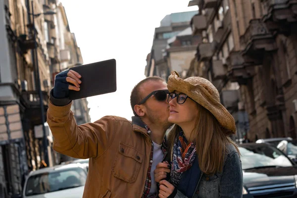 Şehirdeki sokakta selfie çeken genç bir çift..