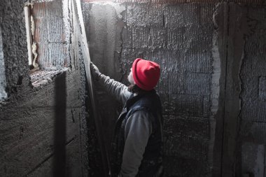 Yeni evin içindeki duvarda çalışan gerçek bir inşaat işçisi..