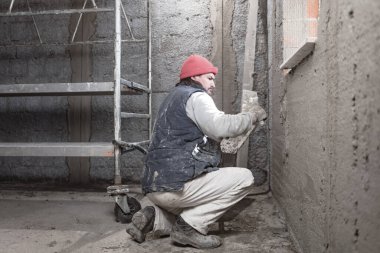 Yeni evin içindeki duvarda çalışan gerçek bir inşaat işçisi..