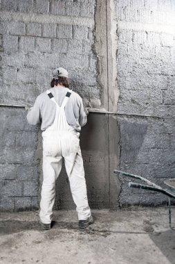 Yeni evin içindeki duvarda çalışan gerçek bir inşaat işçisi..