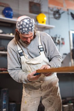Erkek marangoz antika bir atölyede eski ahşap üzerinde çalışıyor..