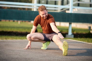 Genç adam şehir parkında koşup egzersiz yaptıktan sonra geriniyor..