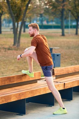 Genç adam şehir parkında koşup egzersiz yaptıktan sonra duraksadı.