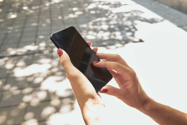 Sokakta modern akıllı telefon kullanan bir kadın..