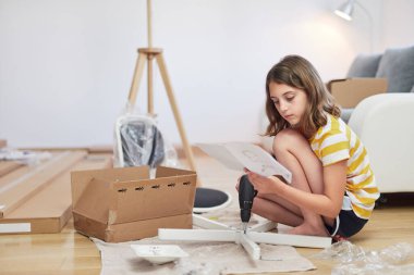 Küçük kız yeni bir evde mobilya montajı yapıyor. Yeni bir eve taşınıyor..