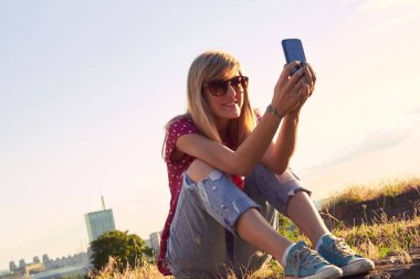 Genç bir kadın açık havada modern akıllı telefon kullanıyor..