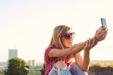 Genç bir kadın açık havada modern akıllı telefon kullanıyor..