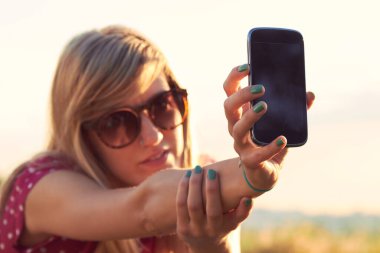 Genç bir kadın açık havada modern akıllı telefon kullanıyor..