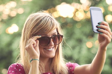 Genç bir kadın açık havada modern akıllı telefon kullanıyor..