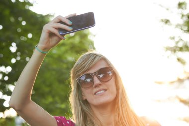 Genç bir kadın açık havada modern akıllı telefon kullanıyor..