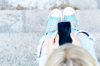 Genç bir kadın açık havada modern akıllı telefon kullanıyor..