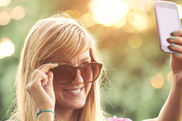 Genç bir kadın açık havada modern akıllı telefon kullanıyor..