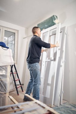 Genç yetişkin bir adam, yeni evinin DIY bütçe tadilatında resim yapıyor..