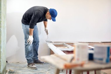 Genç yetişkin bir adam, yeni evinin DIY bütçe tadilatında resim yapıyor..