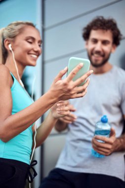 İki sportif genç, kentsel alanda koşup egzersiz yaptıktan sonra duraklıyor..