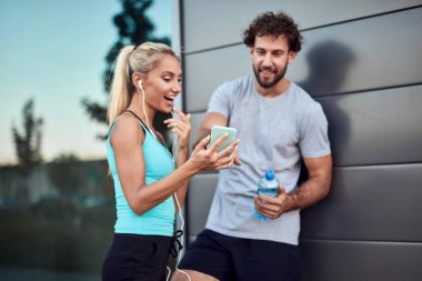 İki sportif genç, kentsel alanda koşup egzersiz yaptıktan sonra duraklıyor..