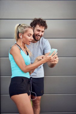 İki sportif genç, kentsel alanda koşup egzersiz yaptıktan sonra duraklıyor..