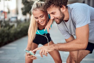 İki sportif genç, kentsel alanda koşup egzersiz yaptıktan sonra duraklıyor..