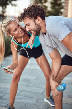 İki sportif genç, kentsel alanda koşup egzersiz yaptıktan sonra duraklıyor..