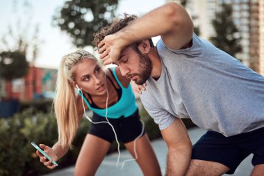 İki sportif genç, kentsel alanda koşup egzersiz yaptıktan sonra duraklıyor..