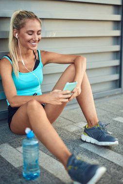 Genç sarışın sporcu, şehir ortamında koşup egzersiz yaptıktan sonra ara veriyor..