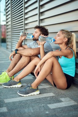 İki sportif genç, kentsel alanda koşup egzersiz yaptıktan sonra duraklıyor..