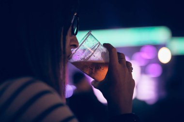 Bir müzik festivalinde elinde soğuk bira bardağı tutan biri..