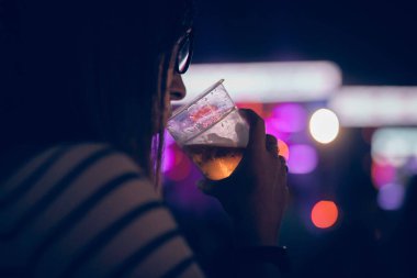 Bir müzik festivalinde elinde soğuk bira bardağı tutan biri..