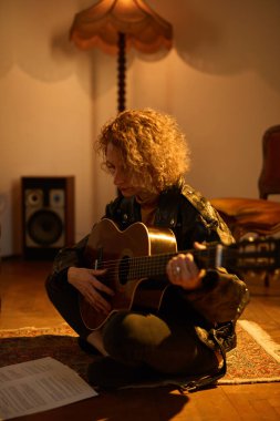 Eski moda bir odada akustik gitar çalan bir kadın..