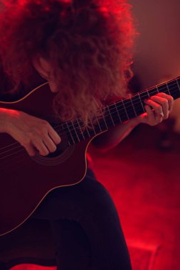 Eski moda bir odada akustik gitar çalan bir kadın..