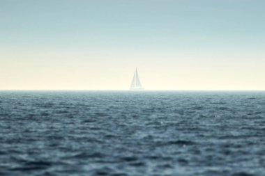 Yelkenli tekne ve ufukta mavi okyanus suyu.