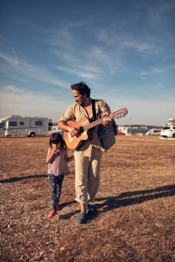 Baba ve kız müzik çalıyor, şarkılar söylüyor ve yaz havasının tadını çıkarıyor..