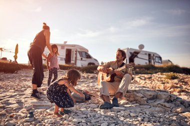 Tatilde bir aile, şarkı söylemek, gitarda müzik çalmak ve yaz havasının tadını çıkarmak..