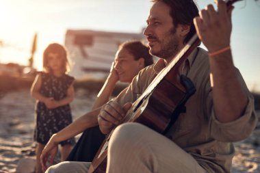 Tatilde bir aile, şarkı söylemek, gitarda müzik çalmak ve yaz havasının tadını çıkarmak..