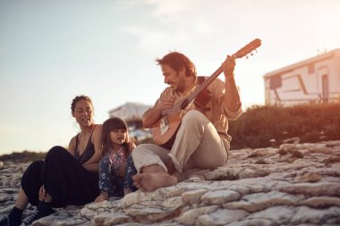 Tatilde bir aile, şarkı söylemek, gitarda müzik çalmak ve yaz havasının tadını çıkarmak..