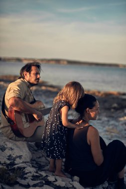 Tatilde bir aile, şarkı söylemek, gitarda müzik çalmak ve yaz havasının tadını çıkarmak..