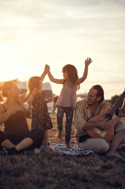 Tatilde bir aile, şarkı söylemek, gitarda müzik çalmak ve yaz havasının tadını çıkarmak..