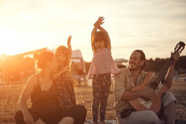 Tatilde bir aile, şarkı söylemek, gitarda müzik çalmak ve yaz havasının tadını çıkarmak..
