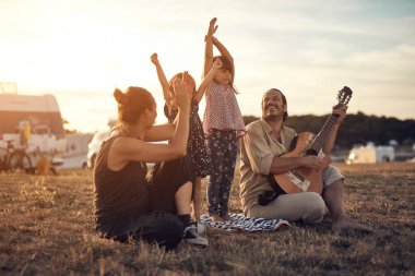 Tatilde bir aile, şarkı söylemek, gitarda müzik çalmak ve yaz havasının tadını çıkarmak..