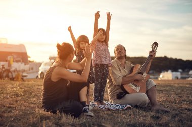 Tatilde bir aile, şarkı söylemek, gitarda müzik çalmak ve yaz havasının tadını çıkarmak..