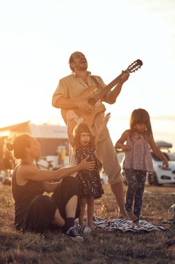 Tatilde bir aile, şarkı söylemek, gitarda müzik çalmak ve yaz havasının tadını çıkarmak..