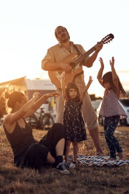 Tatilde bir aile, şarkı söylemek, gitarda müzik çalmak ve yaz havasının tadını çıkarmak..