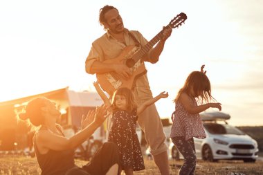 Tatilde bir aile, şarkı söylemek, gitarda müzik çalmak ve yaz havasının tadını çıkarmak..